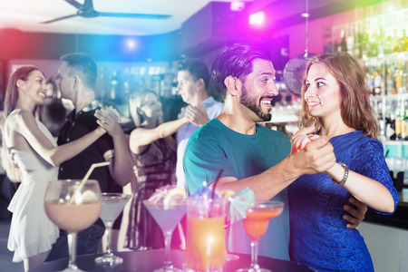 Young joyous women with men are dancing in pairs ?n the dance floor in the nightclubの写真素材