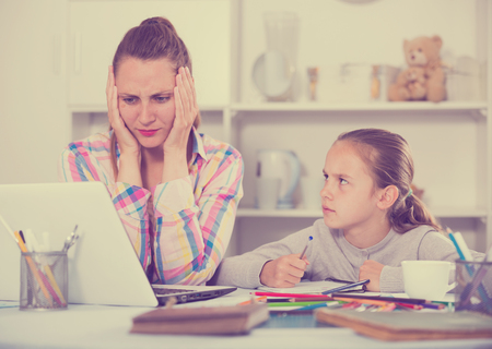 Irritated mother watching at the mistakes her daughter's homeworkの写真素材