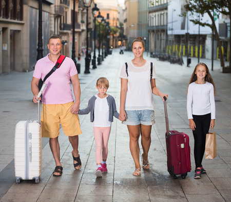 Nice family with two children walking around city with suitcasesの写真素材