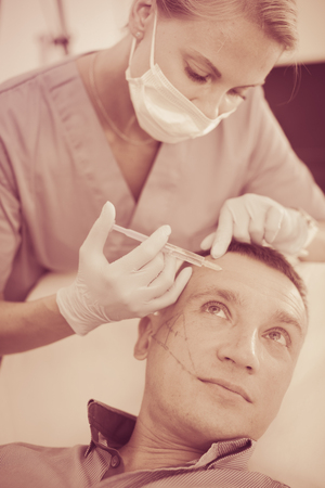 Female doctor is doing injection to patient in skin of face in estetic clinic.の写真素材
