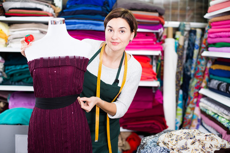 Young woman tailor taking measurements from dress at studioの写真素材