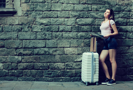 Smiling woman with travelling bag on stone wall background outdoorsの写真素材