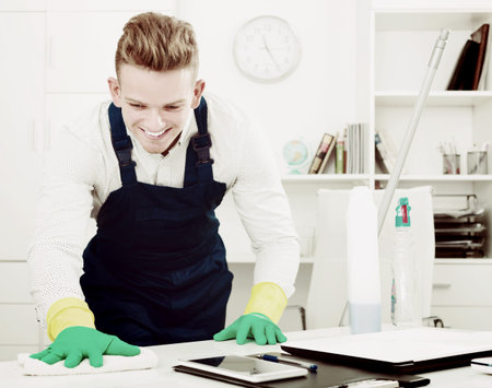 Smiling young man in overall with supplies doing professional clean-up