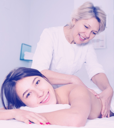Young smiling woman having professional massage in spa salonの写真素材