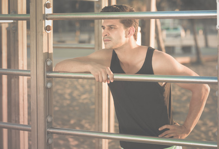 Lifestyle portrait of muscular man in sportswear near fitness station on beachの写真素材