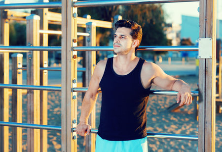 Confident athletic cheerful positive  man taking break during morning workout outdoor
