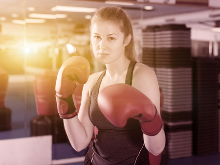 Portrait of adult serious woman boxer who is training in gym.の写真素材