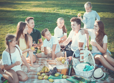 Portrait of happy cheerful positive  parents with children on picnic in nature at summerの写真素材