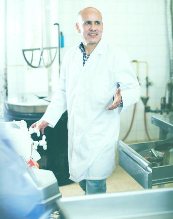 Middle aged worker standing near the table in food manufactureの写真素材