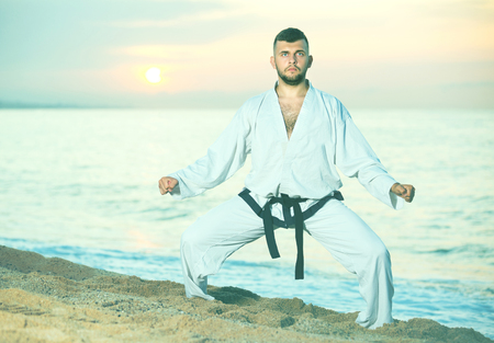 Young man is training the Shiko-dachi stance on the beach near the sea.の写真素材