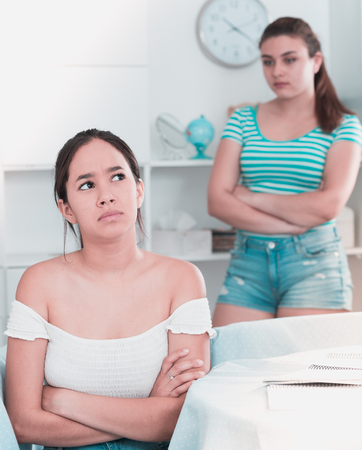 Two offended teens girls not talking to each other after quarrel at homeの写真素材