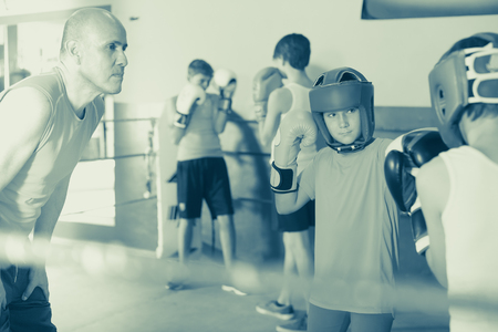 Group of children practicing with instructor on boxing ring at gymの写真素材