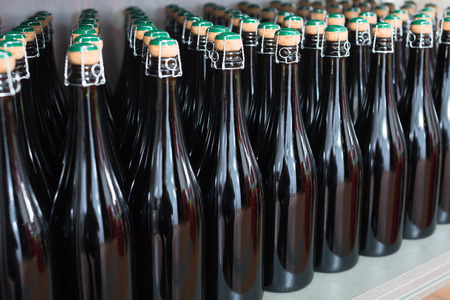 Lines of sparkling wine bottles on display on shelfの写真素材