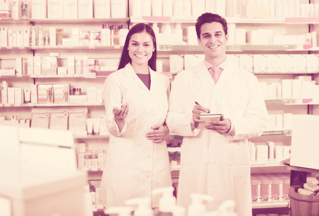 Positive pharmacist and pharmacy technician posing in drugstoreの写真素材