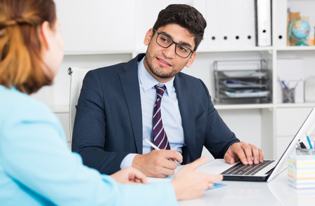 Successful businessman in glasses talking to female colleague in officeの写真素材