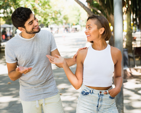 Positive  glad man and woman talking and smiling at the streetの写真素材
