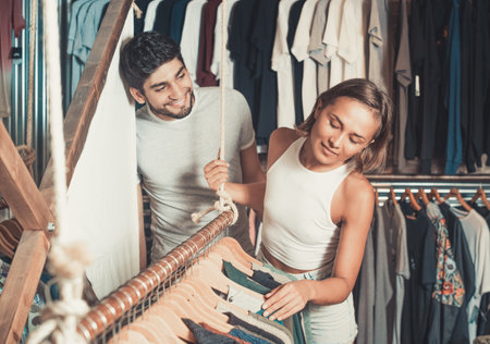 glad adult male and female holding colorful dress in the boutiqueの写真素材