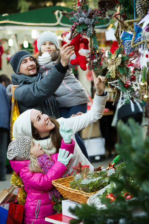 Family of four choosing floral christmas decorations at market. Focus on woman and girlの写真素材