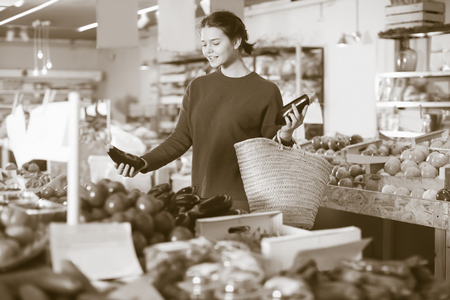 Ordinary girl buying ripe aubergines at marketの写真素材
