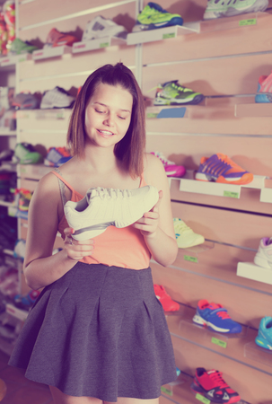 Smiling young sportswoman buying professional shoes in sport storeの写真素材