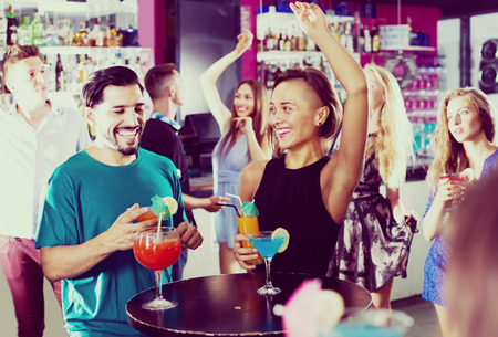 active male with female are talking and drinking cocktails on the party in clubの写真素材