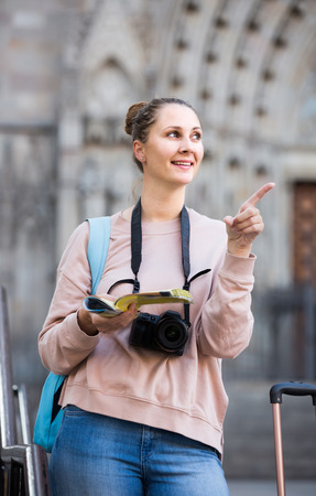 happy young girl having pamphlet and looking for her route in   cityの写真素材