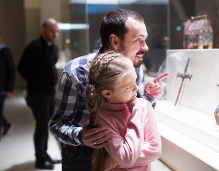 Smiling father and daughter regarding religious art in museum