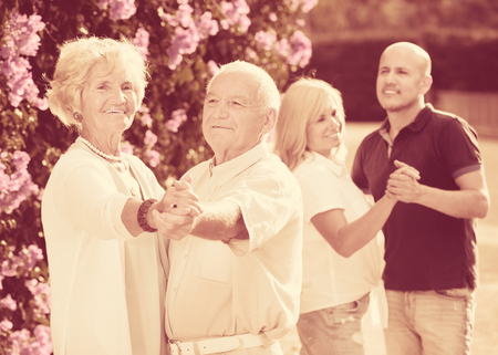 Mature friends dancing the walts in green gardenの写真素材
