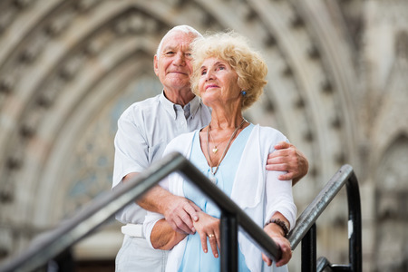 Portrait of happy mature woman with husband posing near iron banisters outdoorsの写真素材