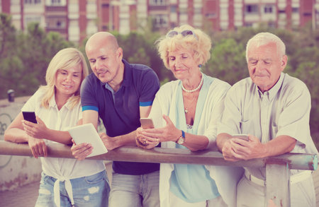 Four positive people texting in smartphones in the garden