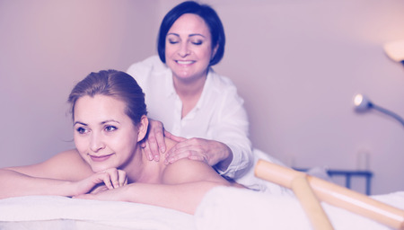 Glad woman on massage procedure in Spa salon where bamboo sticks are usedの写真素材