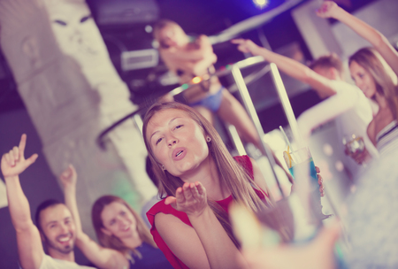 Smiling woman dancing in the night club with drinks in a handの写真素材