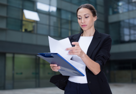 Businesswoman is examining documents before signing outdoors.の写真素材