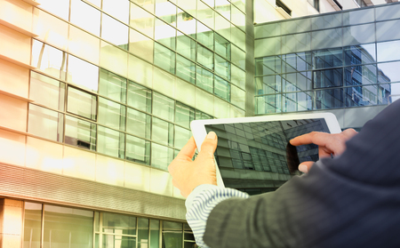 Female hands with digital tablet on background with large factoryの写真素材