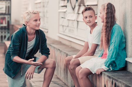 Group of positive children relaxing and chatting in town square gardenの写真素材