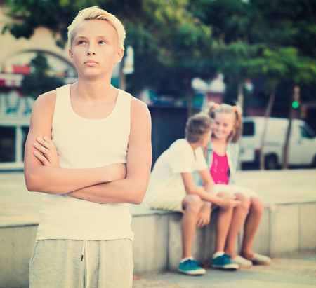 Portrait of offended boy not talking with friends after quarrel outdoorsの写真素材