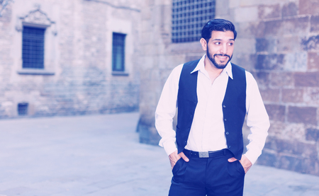 Waist up portrait of confident young man against old stone castleの写真素材