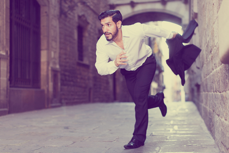 Handsome bearded hurrying man running along old town streetの写真素材