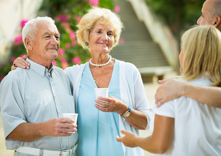 Mature friends  relax and drink tea at plastic cup in the gardenの写真素材