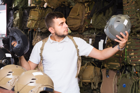 Young positive european guys choosing helmet in military shopの写真素材