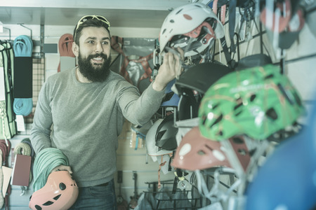 Young guy rejoice to consider helmets in a sports equipment storeの写真素材
