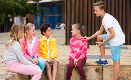Two boys and three girls are talking about play on walk in the park.の写真素材