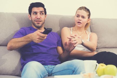 Young upset woman trying to take away TV remote from her boyfriendの写真素材