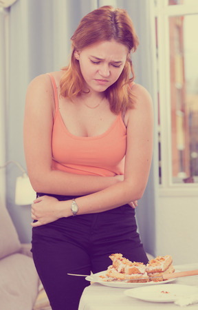 Female is overeating and she sitting unhappy at home.の写真素材