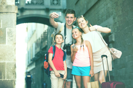 Beautiful tourist family of four strolling on city streets and taking selfie