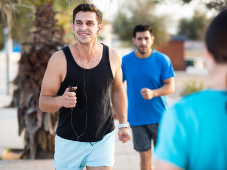 Smiling sportsmen are joggning race in time warm-up in the park near beach.