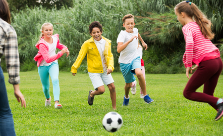 Happy children are jogning and playing football in the park.の写真素材