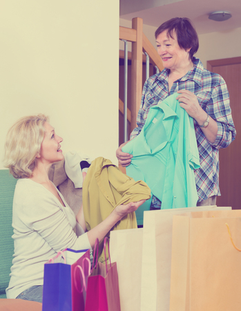 Smiling pensioner bragging with new blouse in front of happy friendの写真素材