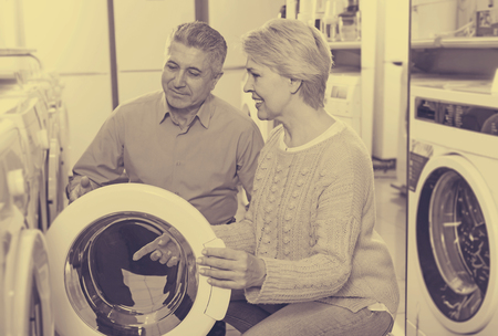 Mature husband with wife are choosing home modern washing machineの写真素材