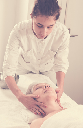 Mature woman client having face massage procedure in beauty salonの写真素材